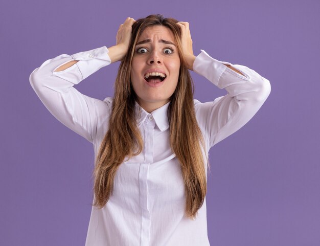 Anxious young pretty caucasian girl puts hands on head isolated on purple wall with copy space