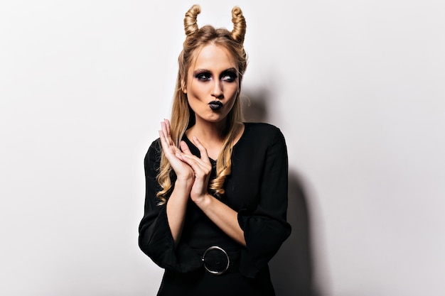 Free photo appealing caucasian woman in vampire attire posing in carnival. pretty wizard in black dress enjoying halloween.