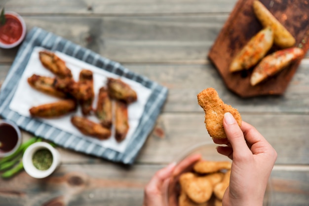 Appetizing crumbed chicken snack held by person