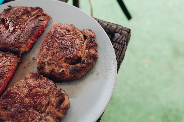 Appetizing grilled fresh steak medium roasted on white plate surrounded by green grass