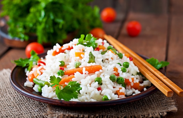 Free Photo appetizing healthy rice with vegetables in white plate on a wooden table.