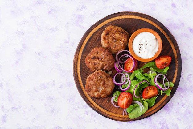 Appetizing meat cutlet and tomato salad with arugula