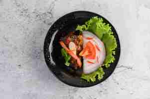 Free photo appetizing spicy canned sardine salad in spicy sauce in black ceramic bowl