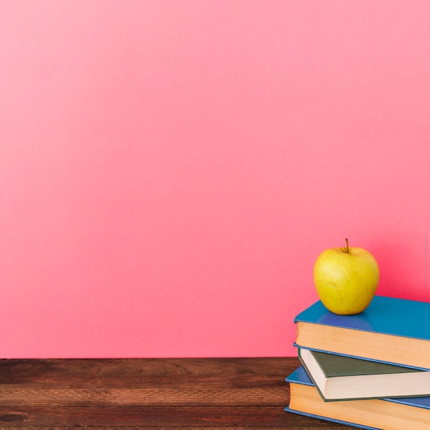 Apple and books near pink wall