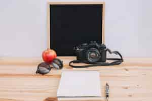 Free photo apple and camera near notepad and blackboard