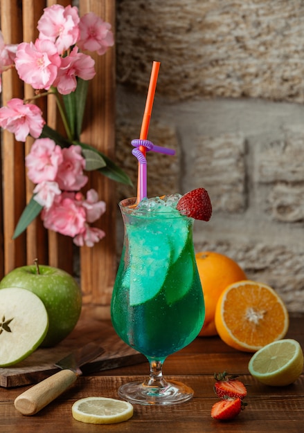 Apple cocktail with apple slices and ice, garnished with strawberry