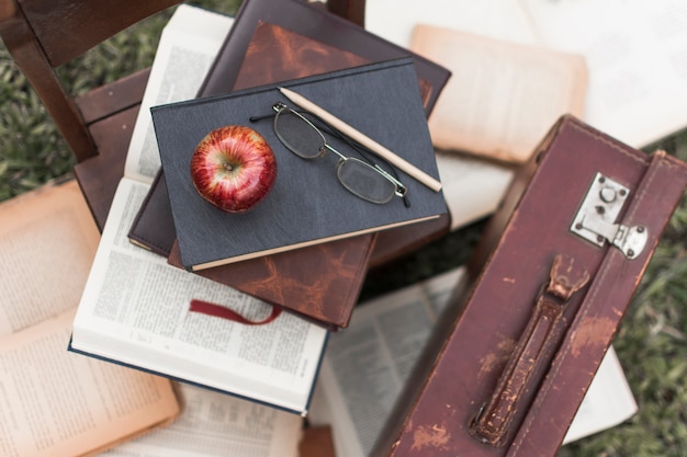 Free photo apple and glasses on books near suitcase