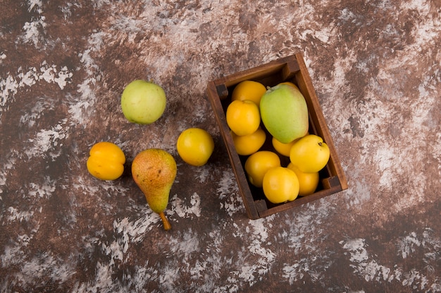 Apple, pear and peaches in a wooden box, top view