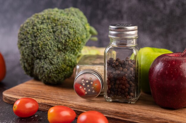 Apple on a wooden board with a jar of pepper seeds