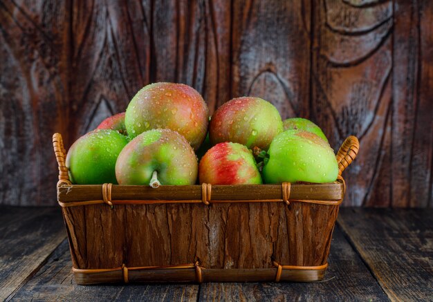 Apples in a basket on old wooden background. side view.