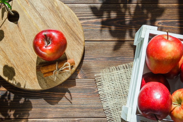 Free photo apples in a white box and apple with cinnamon sticks on cutting board