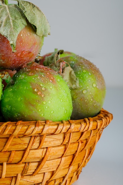 Free photo apples in a wicker basket with leaves close-up on white