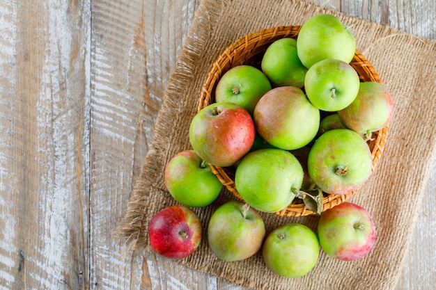 Free Photo apples in a wicker basket on wooden and piece of sack.