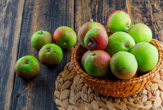 Apples in a wicker basket on wooden and placemat background. high angle view.