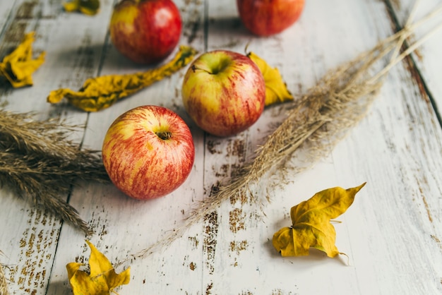 Free Photo apples with dry leaves on shabby table