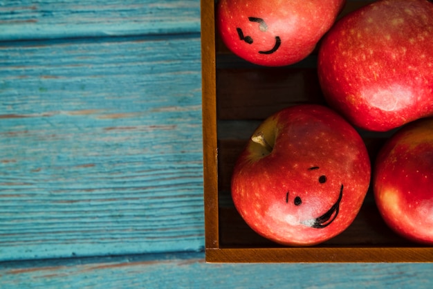 Free photo apples with funny faces in wooden box