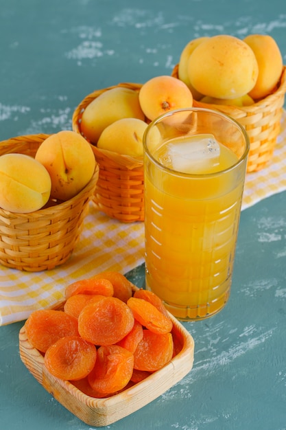 Free photo apricots in baskets with dried apricots, juice top view on plaster and picnic cloth