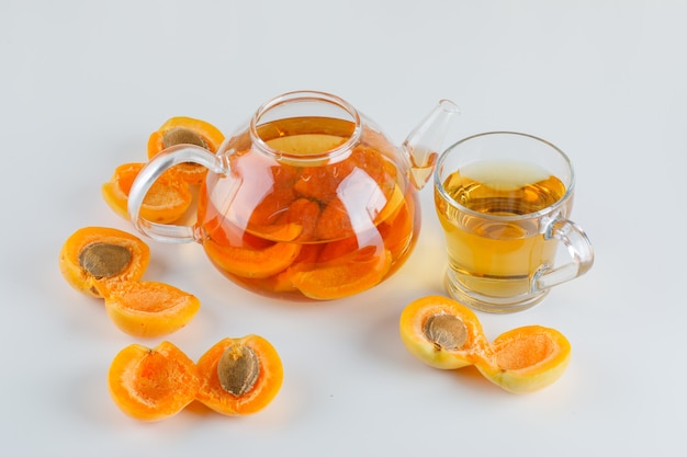 Apricots with tea on white table, top view.