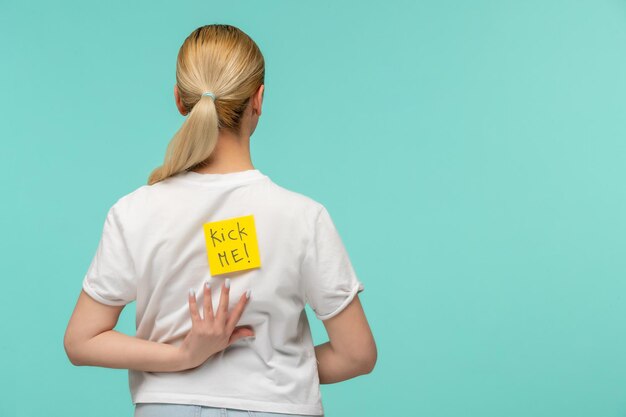 April fools day blonde girl reaching one hand on back yellow post it sticker note kick me funny