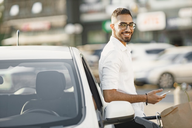 Arab man use smart phone while waiting for charging the battery in car. Eco awarness.