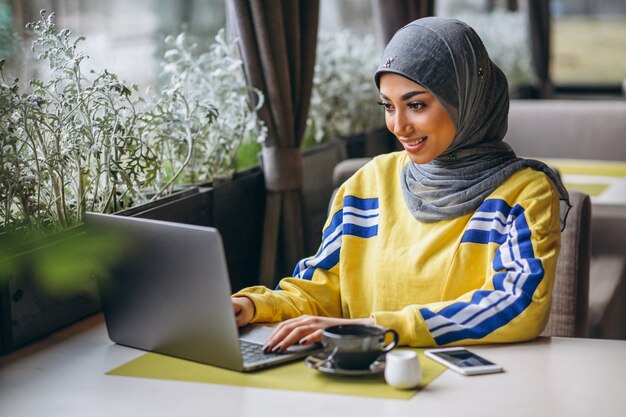 Arabian woman in hijab inside a cafe working on laptop