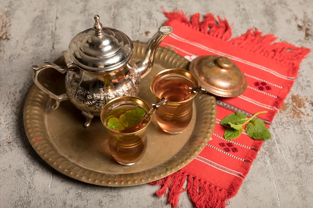 Arabic tea in glasses with teapot on red cloth