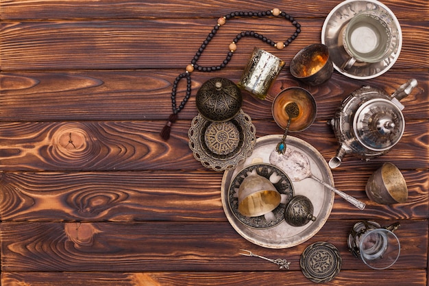 Arabic teapot with cups and beads on table