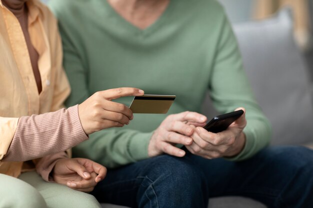 Arabic woman teaching senior man to use mobile pay with credit card