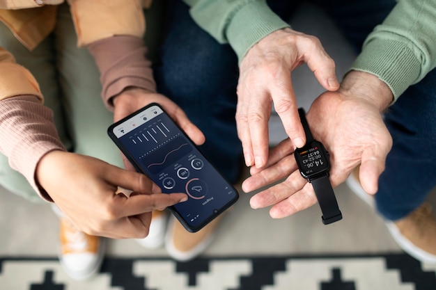 Free photo arabic woman teaching senior man to use smartwatch with smartphone