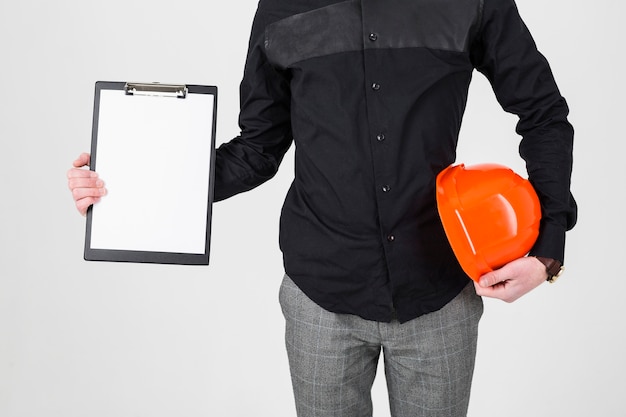 An architect holding clipboard and hardhat over white background