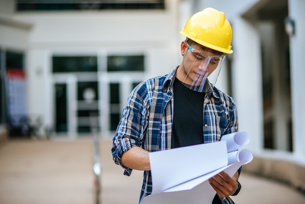 Architects hold the building plan and check the work.