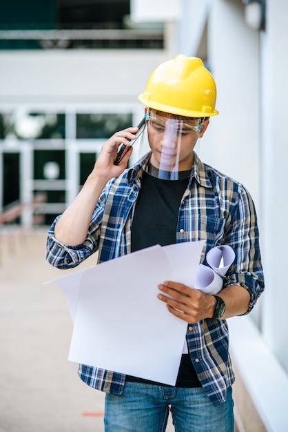 Free photo architects hold floor plans and talk on the phone.