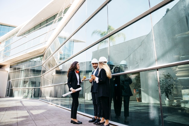 Architects wearing helmets in front of glass building