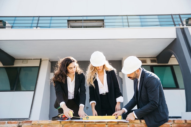 Free photo architects wearing helmets looking at a plan