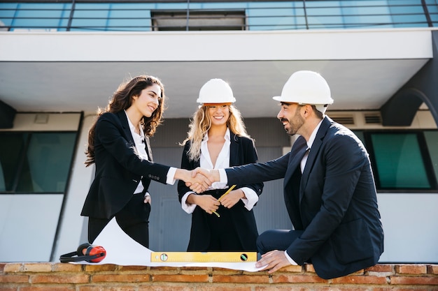 Architects wearing helmets and shaking hands