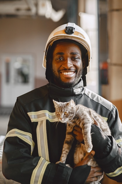 Arfican fireman in a uniform. Man prepare to work. Guy with kitty.