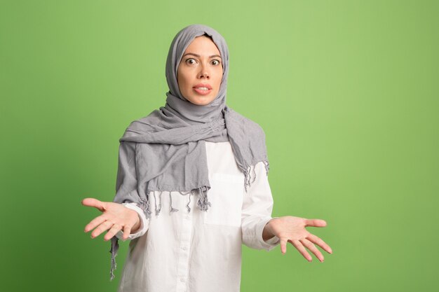 Argue, arguing concept.arab woman in hijab. Portrait of girl, posing at green studio background. Young emotional woman. The human emotions, facial expression concept. Front view.