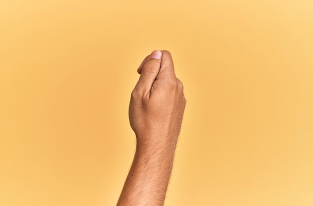 Free photo arm and hand of caucasian man over yellow isolated background holding blank space with thumb finger, business and advertising