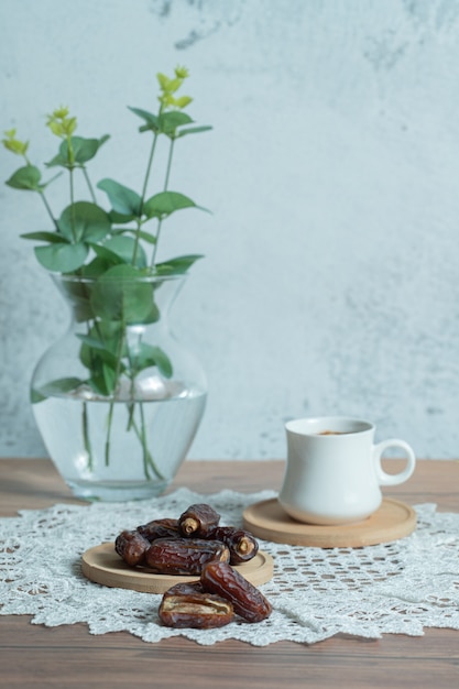 Aroma coffee and delicious dates on wooden table.