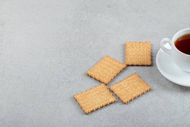 Aroma cup of tea with tasty crackers on a marble surface.