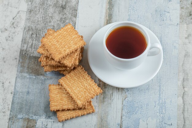 Aroma cup of tea with tasty crackers on a wooden table.