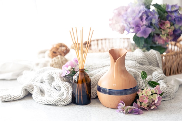 Free photo aroma oil diffuser lamp flowers and knitted element on a blurred background