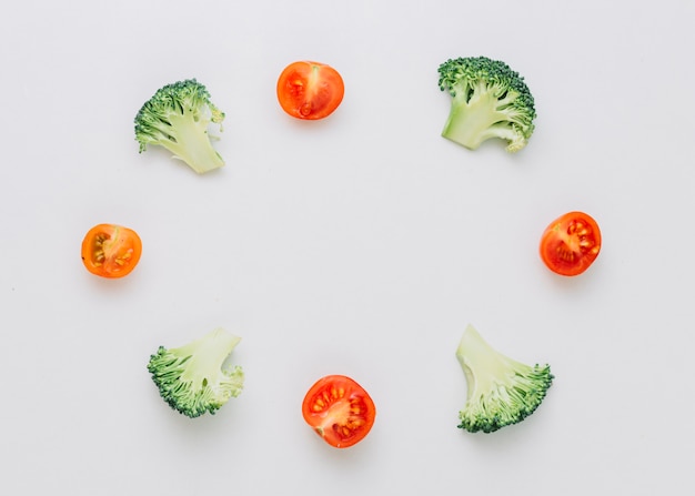 Free Photo arranged halved broccoli and cherry tomatoes in circular frame isolated on white background