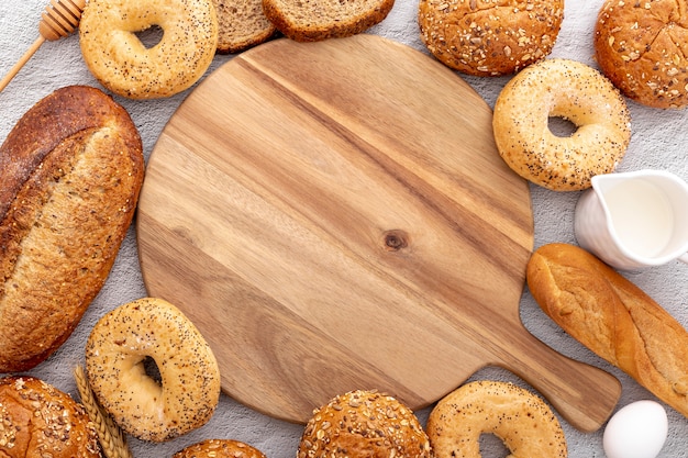 Free photo arrangement of bread surrounding a wooden copy space board