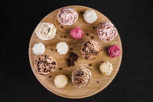 Arrangement of cupcakes and whipped creams on wooden stand