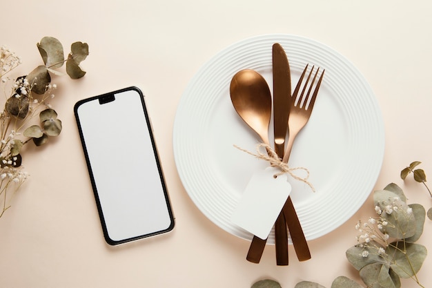 Arrangement of elegant tableware with empty smartphone