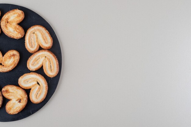 Arrangement of flaky cookies on a black board on white background.