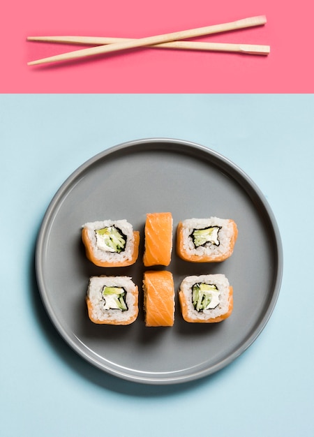 Free photo arrangement of sushi rolls with chopsticks and soy sauce