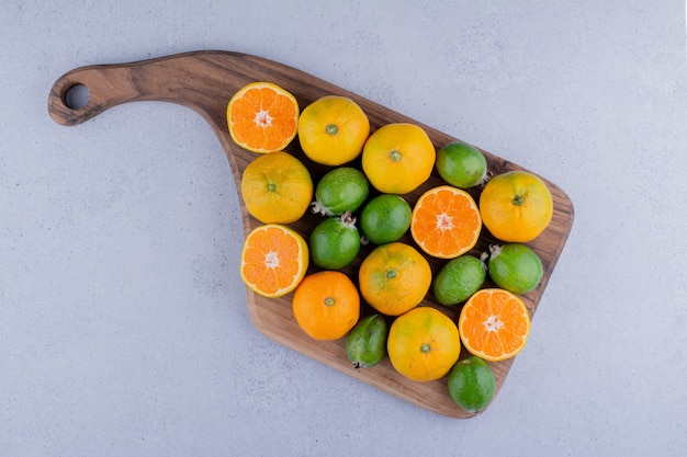 Arrangement of tangerines and feijoas on a board on marble background. High quality photo