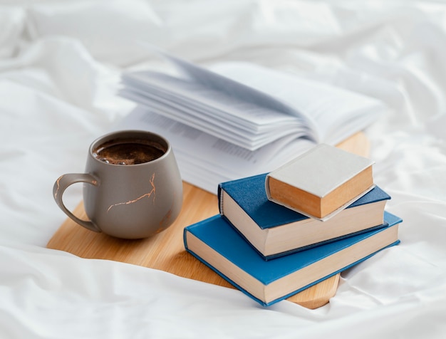 Arrangement with books and cup in bed